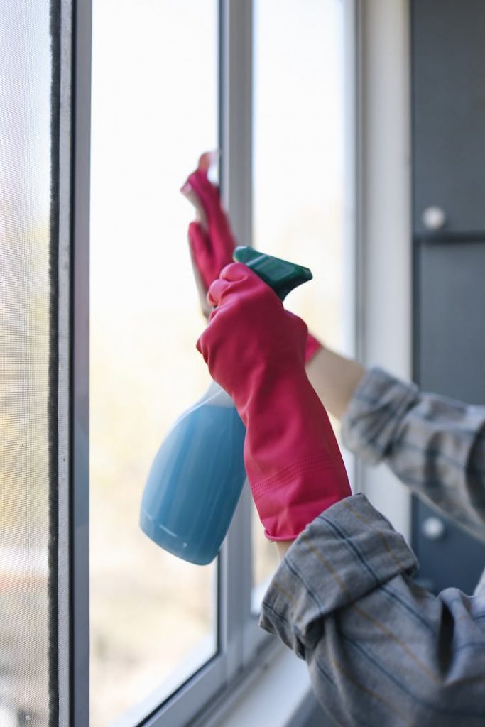Crafting Captivating Headlines: Your awesome post title goes here Hands in rubber gloves using a spray bottle to clean a window indoors.