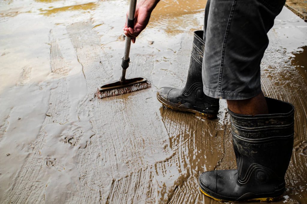 Mastering the First Impression: Your intriguing post title goes here Side view of crop anonymous male worker in gumboots with brush priming cement floor at work